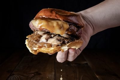 Hamburguesa de La Capital sujeta con la mano